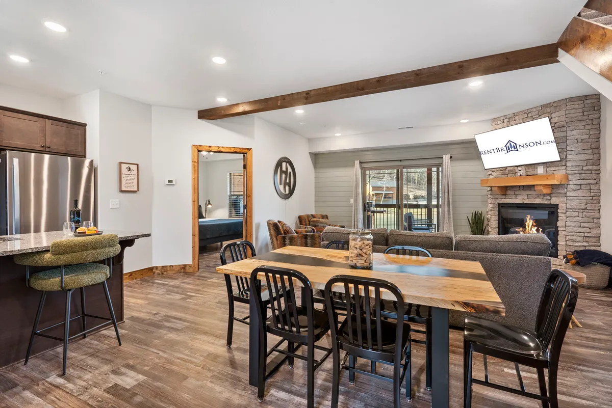An open-concept space combining a dining table, fireplace, kitchen area, and a comfortable seating arrangement. The layout invites shared meals, conversation, and relaxation, with the fireplace adding an extra layer of warmth and welcoming ambiance.